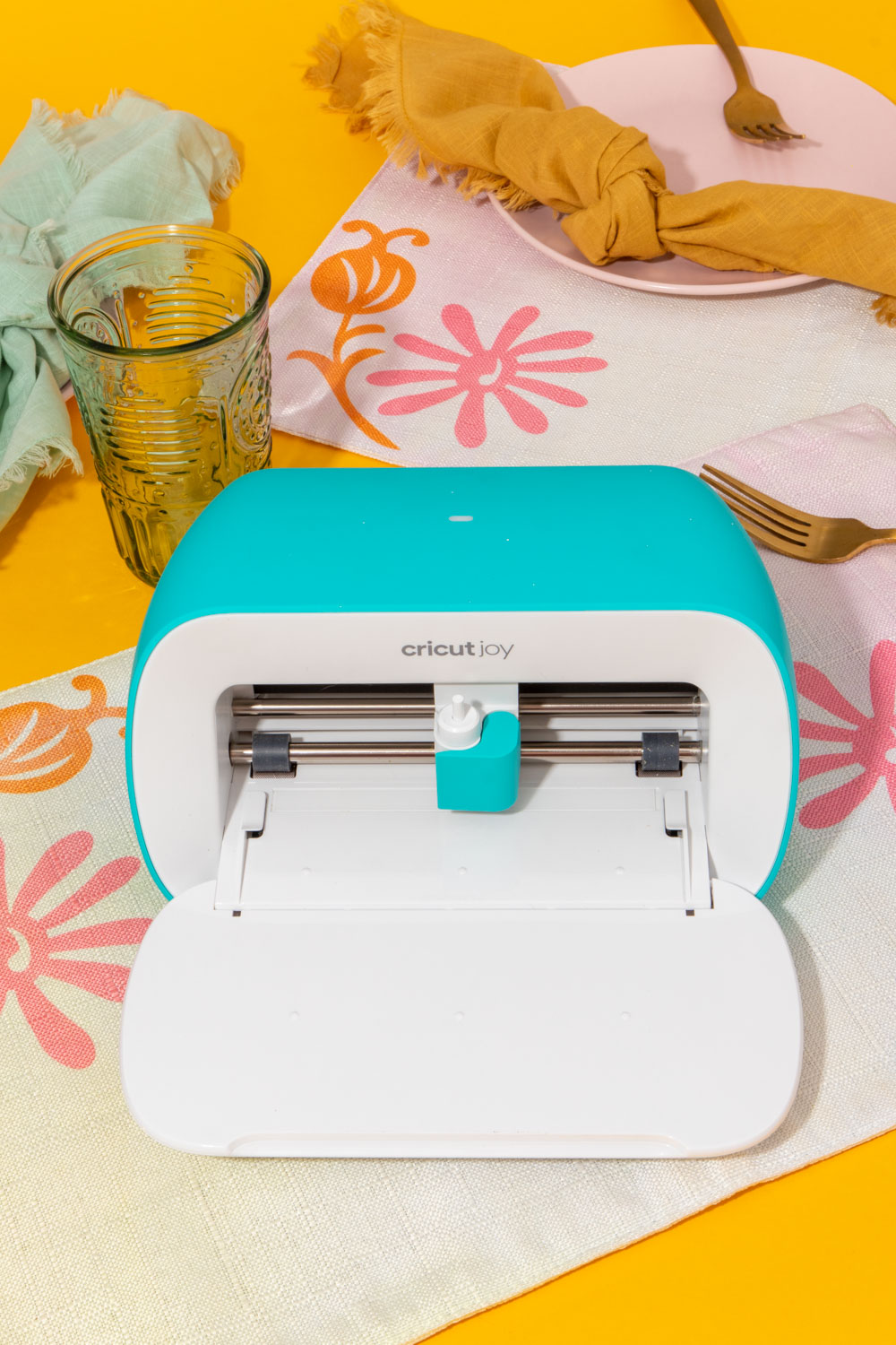 Cricut Joy on top of floral placemat on yellow background